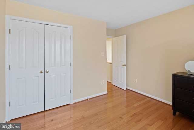 bedroom featuring a closet, light wood-type flooring, and baseboards