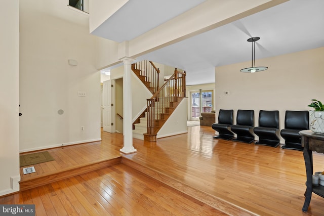 entrance foyer featuring ornate columns, baseboards, stairway, and light wood finished floors