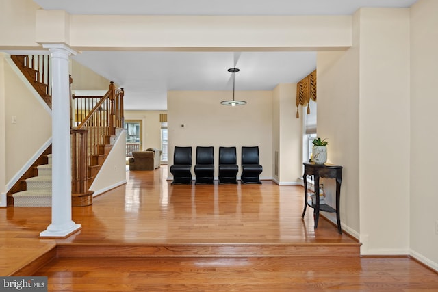 entryway with light wood-type flooring, decorative columns, and baseboards