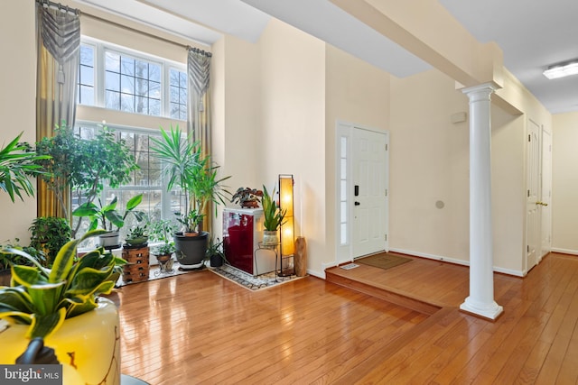 entryway featuring baseboards, light wood-style floors, and ornate columns