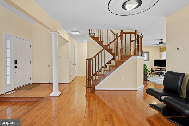 foyer featuring light wood-style floors, decorative columns, stairway, and baseboards