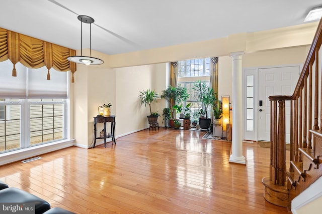 entrance foyer featuring ornate columns, stairway, visible vents, and light wood-style floors