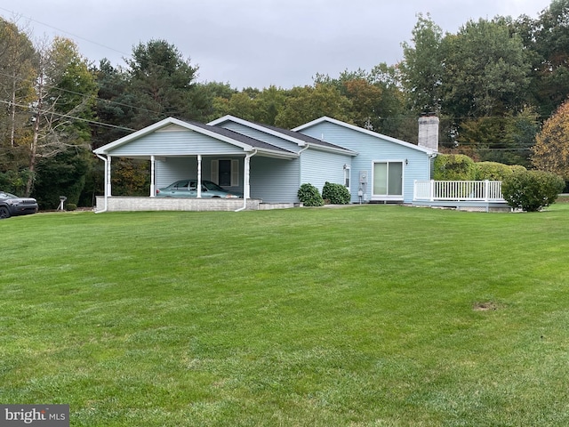 view of front of property with a carport, a chimney, and a front lawn