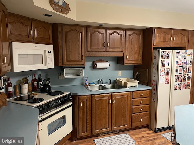 kitchen with visible vents, light countertops, light wood-style flooring, a sink, and white appliances