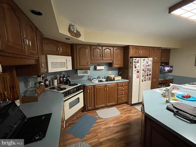 kitchen with brown cabinets, light countertops, light wood-style floors, a sink, and white appliances