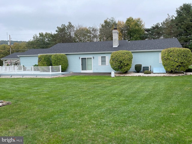 back of house featuring a yard, a shingled roof, a chimney, and a wooden deck