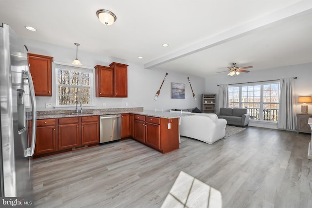 kitchen with appliances with stainless steel finishes, sink, a wealth of natural light, pendant lighting, and kitchen peninsula