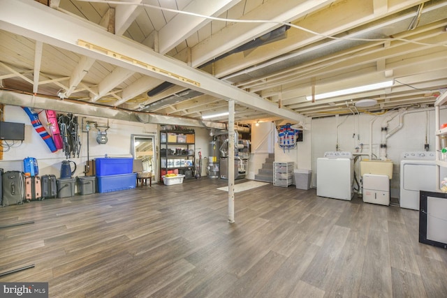 unfinished basement featuring washing machine and dryer, stairs, and wood finished floors