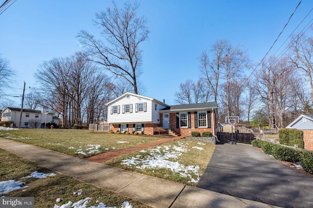 split level home with brick siding, fence, and a front lawn