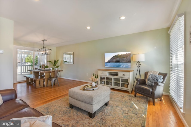 living area with recessed lighting, a notable chandelier, baseboards, and wood finished floors