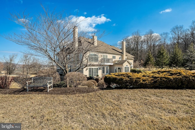 view of home's exterior with a yard, a chimney, and a balcony