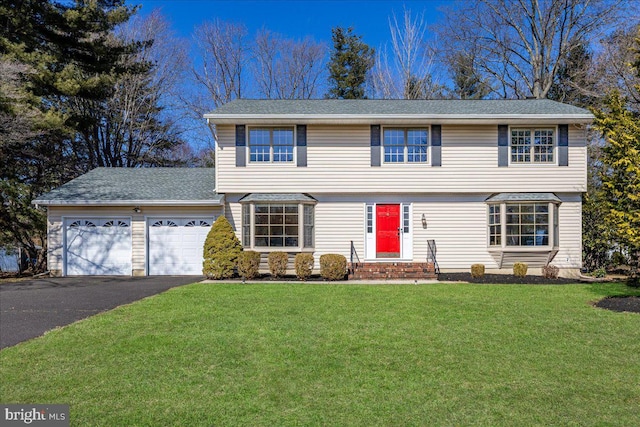 colonial-style house with a garage, a front yard, driveway, and a shingled roof