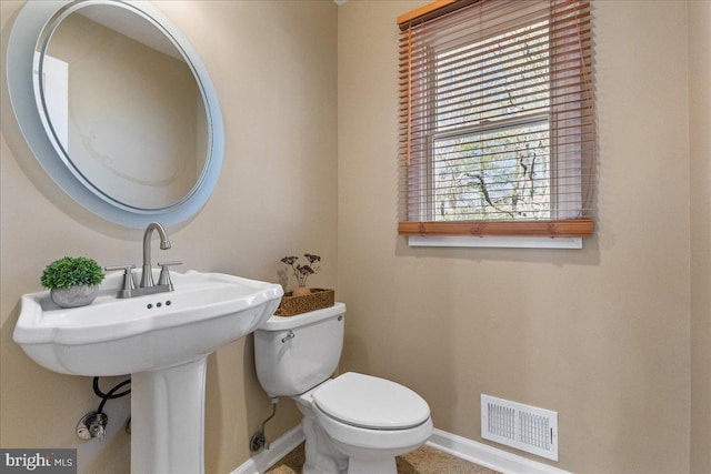 half bathroom featuring baseboards, visible vents, and toilet