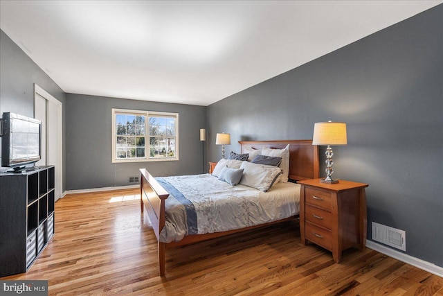 bedroom featuring visible vents, light wood-style flooring, and baseboards