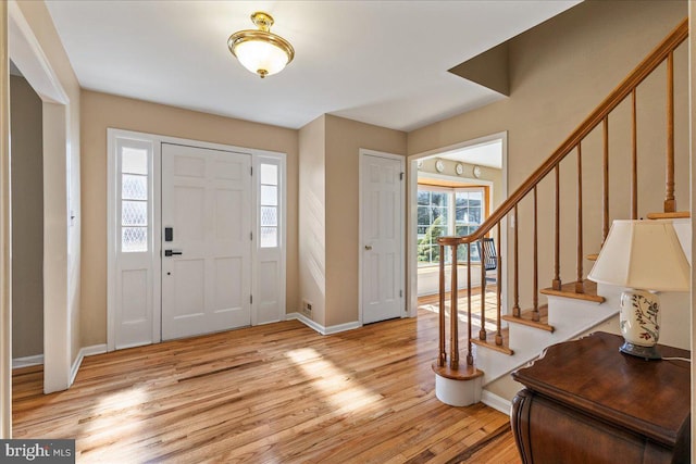 entrance foyer featuring light wood finished floors, stairway, and baseboards