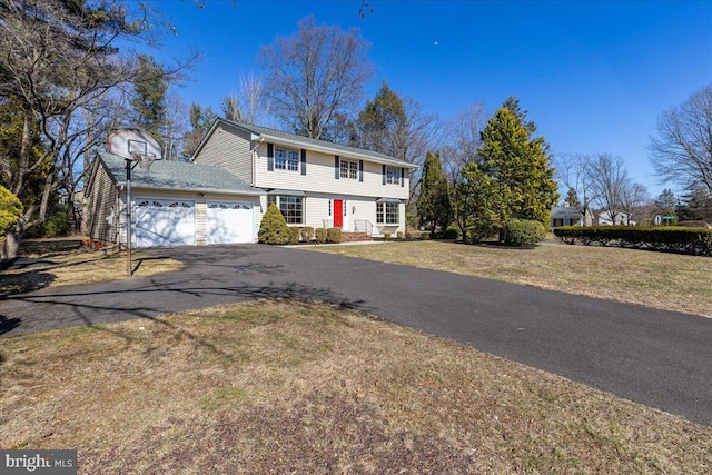 colonial house with a garage, a front lawn, and aphalt driveway