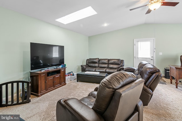 living room featuring lofted ceiling with skylight, light colored carpet, baseboards, and ceiling fan