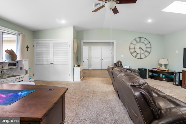 living area with lofted ceiling with skylight, visible vents, a ceiling fan, and carpet