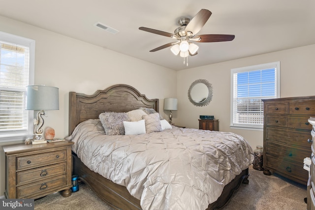 carpeted bedroom featuring a ceiling fan and visible vents