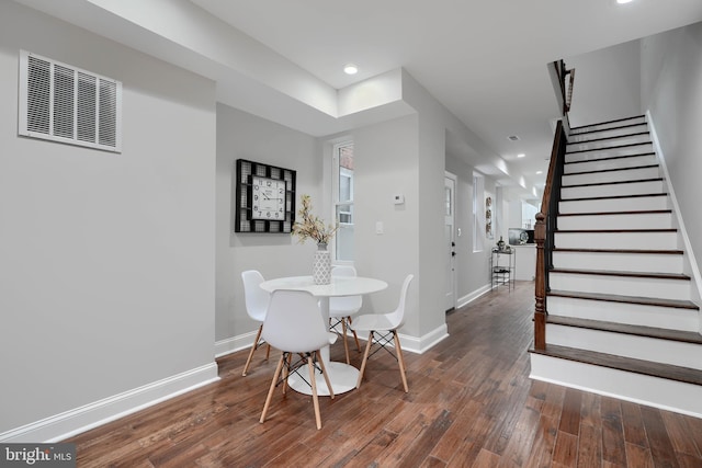 dining space featuring dark wood-style floors, stairway, visible vents, and baseboards