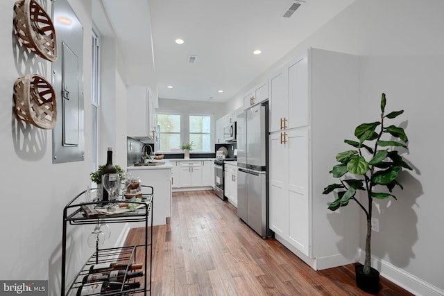 kitchen with white cabinets, wood finished floors, stainless steel appliances, light countertops, and recessed lighting