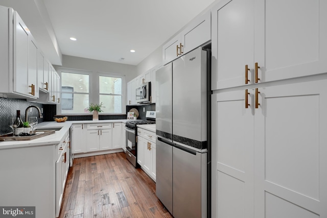 kitchen featuring dark wood-type flooring, a sink, white cabinetry, light countertops, and appliances with stainless steel finishes