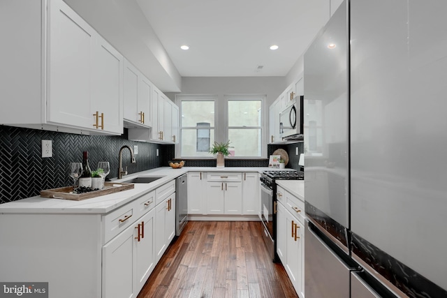 kitchen featuring tasteful backsplash, appliances with stainless steel finishes, a sink, and white cabinets