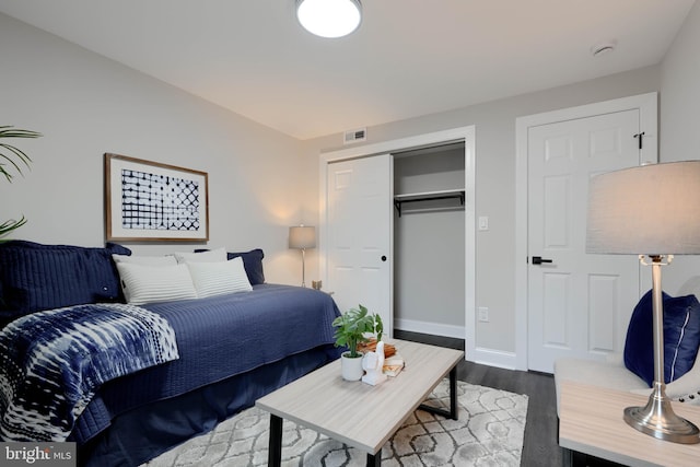 bedroom with a closet, dark wood-style flooring, visible vents, and baseboards