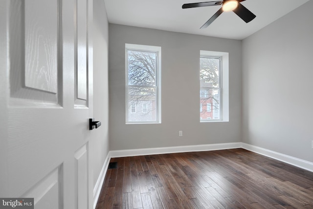 spare room featuring ceiling fan, baseboards, and dark wood finished floors