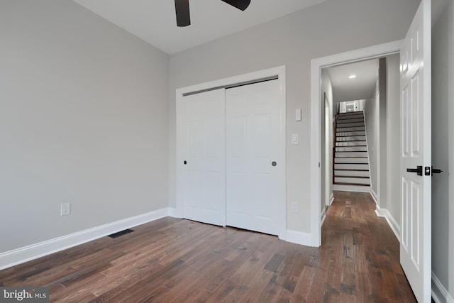 unfurnished bedroom featuring a closet, visible vents, dark wood-type flooring, ceiling fan, and baseboards