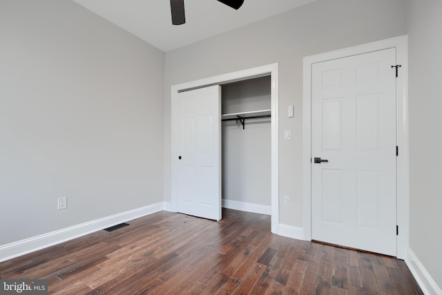 unfurnished bedroom with a closet, dark wood-style flooring, baseboards, and a ceiling fan