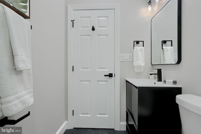 bathroom with toilet, vanity, and baseboards