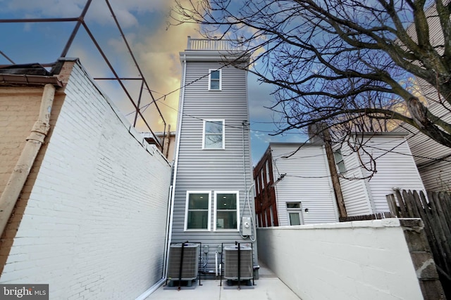 rear view of house with fence and central AC unit