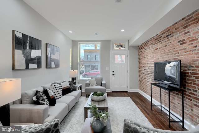 living room with brick wall, baseboards, dark wood-type flooring, and recessed lighting