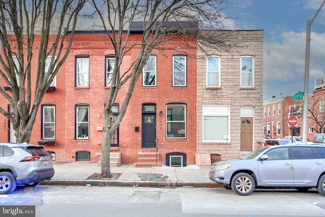 view of property featuring entry steps, stone siding, and brick siding