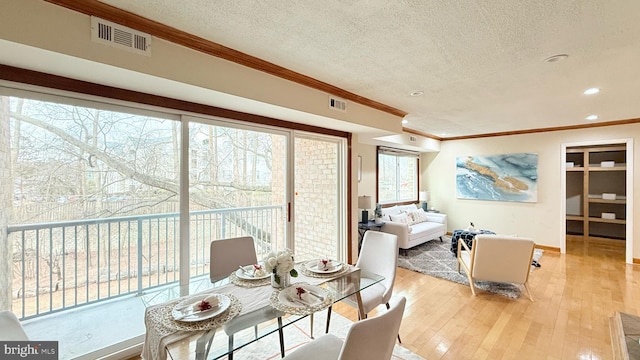 interior space featuring a textured ceiling, crown molding, and light hardwood / wood-style floors