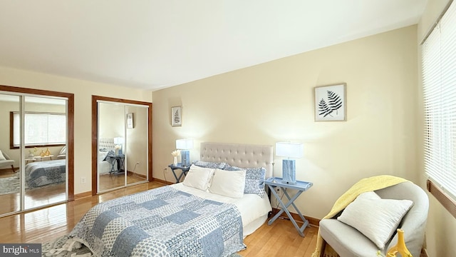 bedroom featuring two closets and light hardwood / wood-style flooring