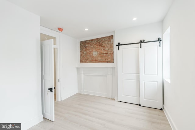 unfurnished bedroom featuring light hardwood / wood-style flooring and a barn door