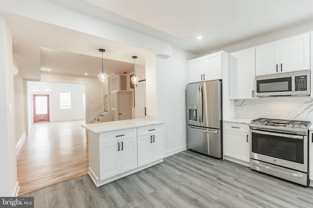 kitchen featuring light hardwood / wood-style flooring, pendant lighting, stainless steel appliances, kitchen peninsula, and white cabinets