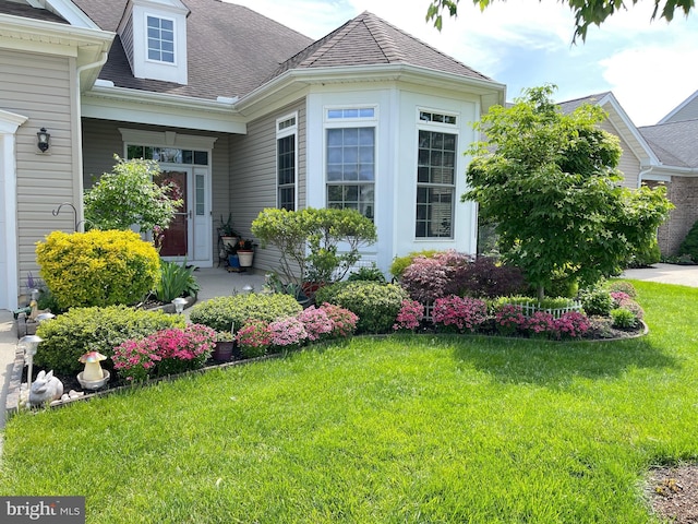 exterior space featuring a shingled roof and a front yard