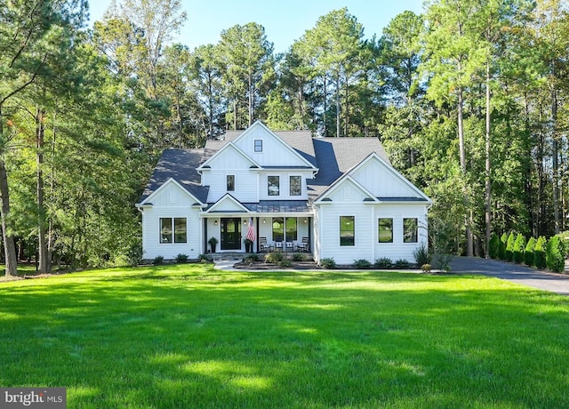 modern farmhouse featuring covered porch and a front yard