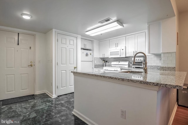 kitchen with white appliances, visible vents, white cabinets, a peninsula, and a sink