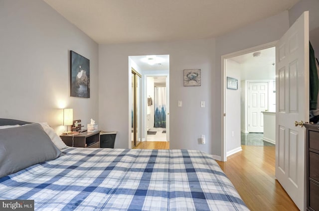 bedroom featuring baseboards, connected bathroom, and light wood-style floors