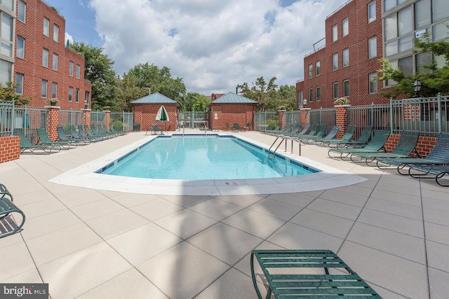 community pool with fence and a patio