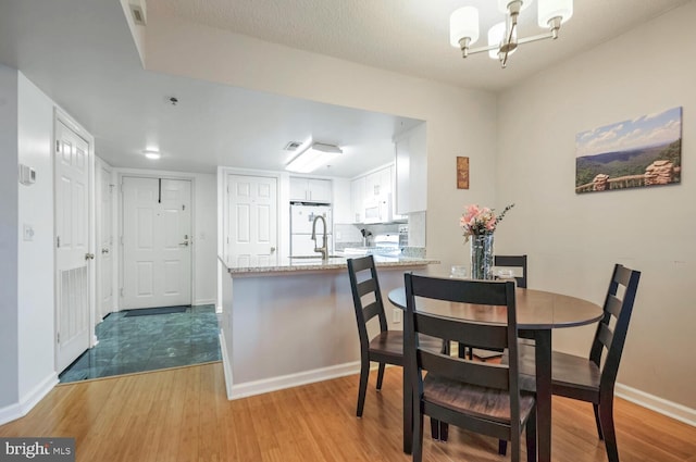 dining space with light wood-style flooring, baseboards, and an inviting chandelier