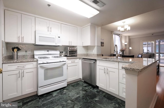 kitchen with a peninsula, white appliances, visible vents, white cabinetry, and decorative light fixtures