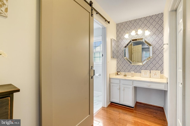 bathroom featuring an accent wall, wood finished floors, vanity, baseboards, and tasteful backsplash