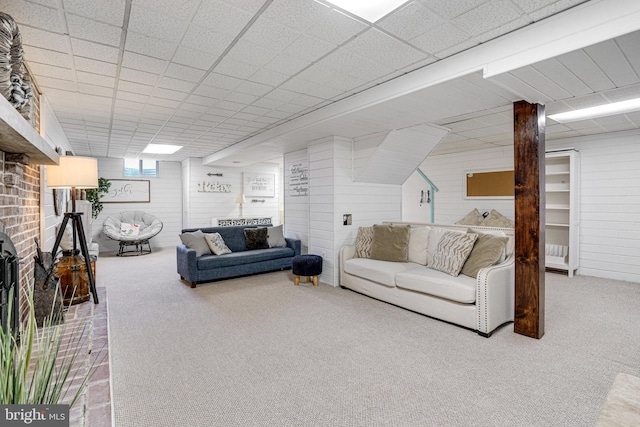 carpeted living area with a paneled ceiling and wooden walls