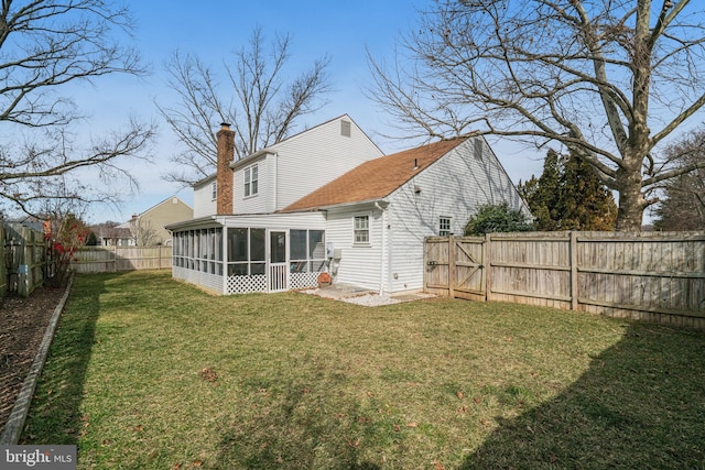 rear view of house with a sunroom, a fenced backyard, a yard, and a chimney