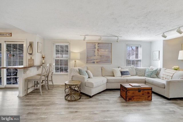 living area with a textured ceiling, light wood finished floors, and baseboards